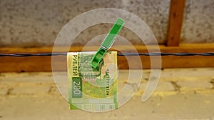 Russian paper banknote of two hundred rubles is attached with a clothespin to a clothesline for drying clothes