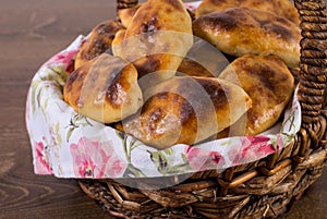 Russian pirozhki (baked patties) in the basket on wooden table