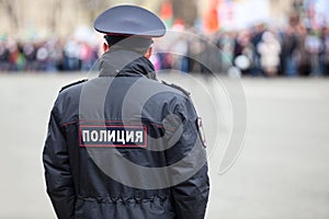 Russian policeman officer stands to opposite crowd with inscription Police on uniform jacket, Russia, copy space