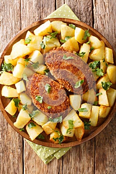 Russian Pozharsky cutlets with a side dish of fried potatoes close-up in a plate. vertical top view