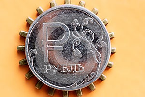 Russian ruble coin on an orange background under the coin pinion prongs act because