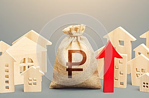 Russian ruble money bag and a city of house figures and red up arrow. Recovery and growth in property prices, high demand.