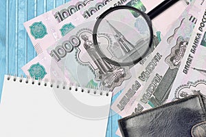 1000 russian rubles bills and magnifying glass with black purse and notepad. Concept of counterfeit money. Search for differences