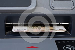 Russian rubles sticking out of an ATM close-up. Cash withdrawal of money from a bank account