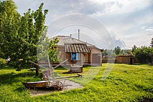 Russian rural house and yard with utensils for the cultivation of land and the well