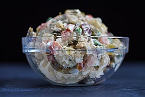 Russian Salad or Salad Olivier in Glass Bowl Dark Background