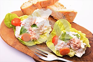 Russian salad with tuna mayonnaise carrots tomato peans starter food on white background and bread and fork photo
