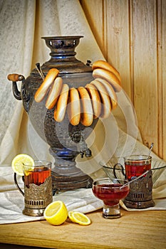 Russian samovar, tea with lemon in faceted glasses with cup holders and bublik. Tinted photo in vintage style