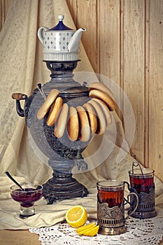 Russian samovar, tea with lemon in faceted glasses with cup holders and bublik. Tinted photo in vintage style