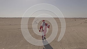 Russian Santa Claus or Ded Moroz with sack walks on sand, found asphalt road in desert. Dlog profile. Aerial view, drone