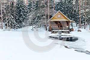 Russian sauna banja house in winter forest nearby the lake with ice-hole