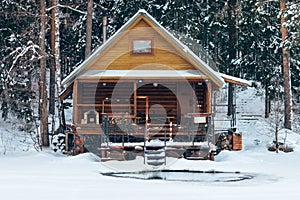 Russian sauna banja house in winter forest nearby the lake with ice-hole photo
