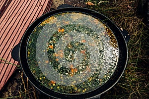 Russian soup, borsch, in a cast iron pot on the background of rye bread, on a wooden table in a stylish restaurant, in