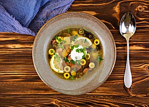 Russian soup solyanka with sour cream on wooden background