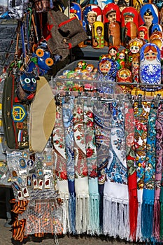 Russian souvenirs such as colorful shawls, scarves, painted matryoshkas, decorative small bags, purses and military headgear lie o
