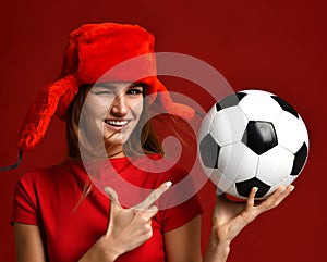 Russian style fan sport woman player in red uniform and ear-flap hat hold soccer ball celebrating happy smiling