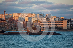 Russian submarine in city harbour with residential buildings at background. Sea NAVY boat