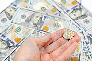 Russian ten ruble coin in a hand on american dollar background, financial loss and impoverishment of people concept