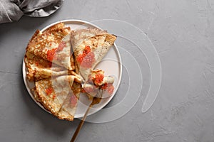 Russian thin pancakes or blini with red caviar on grey.