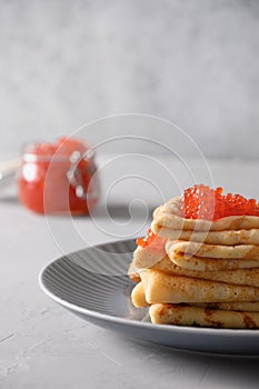 Russian thin pancakes or blini with red caviar on grey.