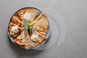 Russian thin pancakes or blini with whipped cream on grey.