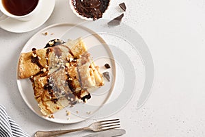 Russian thin pancakes with chocolate topping and nuts.