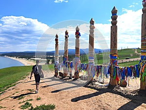 Russian tourist near hitching posts with ribbons of shamanism religion in Khuzhir, island Olkhon.