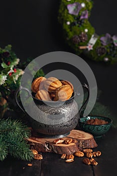 Russian traditional homemade cookies Nuts with condensed milk on an vintage jar on a wooden stand surrounded by spruce branches