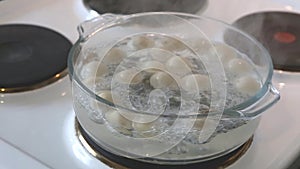 Russian traditional pelmeni are cooked in a glass pot on a stove