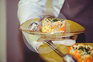 Russian traditional salad Olivier with vegetables and meat. Salad on a golden plate, close-up