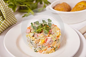 Russian traditional salad Olivier with vegetables and meat in the white plate