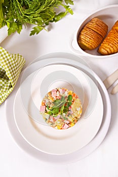 Russian traditional salad Olivier with vegetables and meat in the white plate