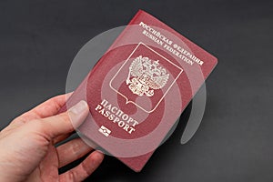 Russian travel passport in a woman's hand on a black background, sanctions, emigration, immigration, tourism concept