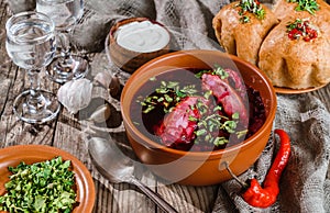 Russian and ukrainian borscht or beet soup with sour cream, buns, garlic on a wooden rustic background with vodka. Close up