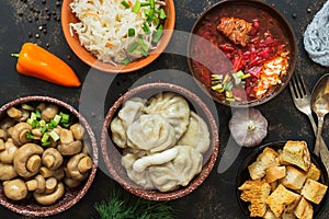 Russian variety of dishes, borsch, dumplings, pickled mushrooms, sauerkraut. Russian food on a rustic background, top view.