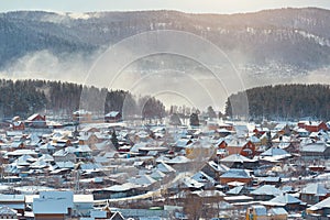 Russian village winter. Roofs covered with snow, a Blizzard sweeps in the forest