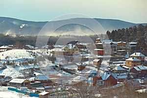 Russian village winter. Roofs covered with snow, a Blizzard sweeps in the forest