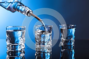 Vodka pouring from the bottle into glass in a bar.