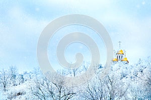 Russian winter landscape. Golden domes of the church against the background of a winter white forest. Snowing