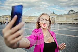 A Russian woman in her 30s takes a photo of herself in front of the sights of St. Petersburg, Russia