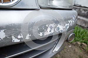 Rust, grime and peeling paint on the front bumper of a car bonnet after years of neglect