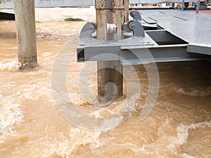 Rust roller support pole of pontoon in rapid stream flowing river