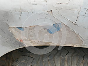 Rust on the side of white old car. Rust hole on old worn painted metal surface