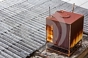 Rust water storage tank on the roof of the house.