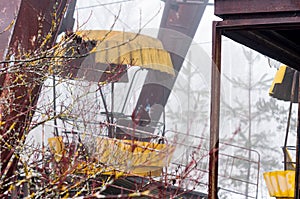 Rust yellow ferris wheel attraction in fog in winter abandoned amusement park Chernobyl zone of alienation