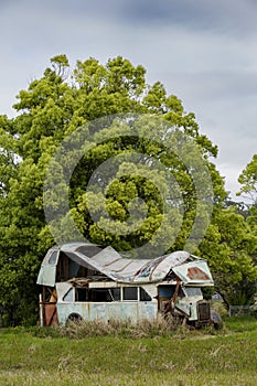Rusted and abandoned bus or truck with severe roof damage