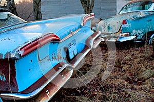 Rusted antique blue cars in field