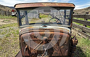 A rusted antique tractor with a broken windshield