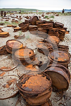 Rusted barrels on the shore.