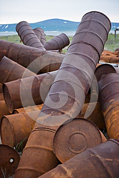 Rusted barrels on the shore.